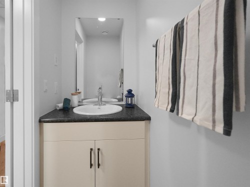 Bathroom vanity featuring a white oval undermount sink, a chrome faucet, and a dark countertop - 403 10115 88 Avenue, Edmonton, AB - Indoor Photo Showing Bathroom