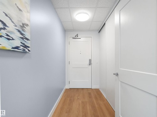 Entryway featuring wood-finish flooring, light blue wall paint, a white paneled door, and a flush-mount ceiling light - 403 10115 88 Avenue, Edmonton, AB - Indoor Photo Showing Other Room