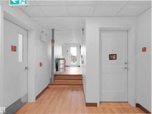 Bright hallway featuring wood-finish flooring, white walls, and a dropped acoustic panel ceiling - 403 10115 88 Avenue, Edmonton, AB - Indoor Photo Showing Other Room