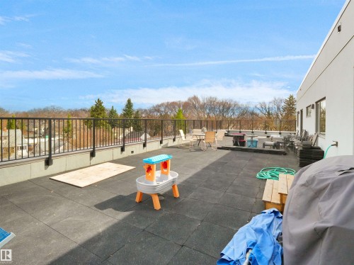 Expansive rooftop terrace featuring dark square paver flooring and a metal railing perimeter - 403 10115 88 Avenue, Edmonton, AB - Outdoor