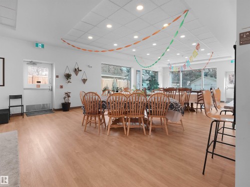 Spacious common area featuring wood-finish flooring, recessed lighting, expansive windows, and a drop ceiling - 403 10115 88 Avenue, Edmonton, AB - Indoor