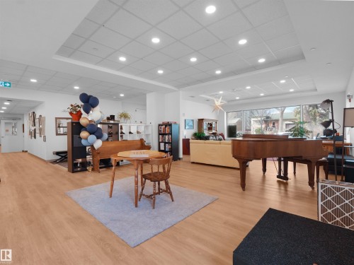 Spacious common area featuring light wood-finish flooring, recessed lighting, and large windows - 403 10115 88 Avenue, Edmonton, AB - Indoor Photo Showing Other Room