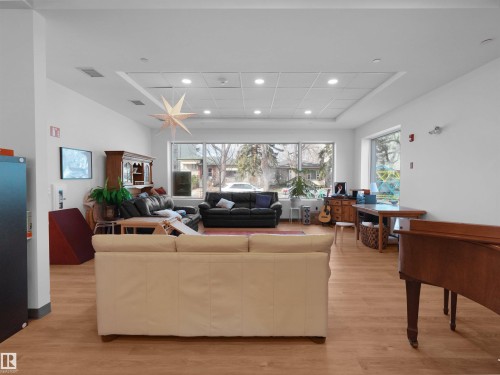 Spacious common area featuring wood-finish flooring, white walls, and a dropped ceiling with recessed lighting - 403 10115 88 Avenue, Edmonton, AB - Indoor