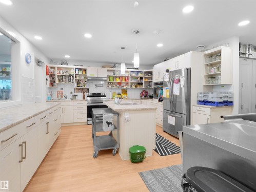 Expansive kitchen with wood-finish flooring, light-toned cabinetry with modern hardware, and a large center island - 403 10115 88 Avenue, Edmonton, AB - Indoor Photo Showing Kitchen With Upgraded Kitchen