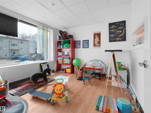 Spacious room featuring large windows, wood-finish flooring, a suspended ceiling, and recessed lighting - 403 10115 88 Avenue, Edmonton, AB - Indoor