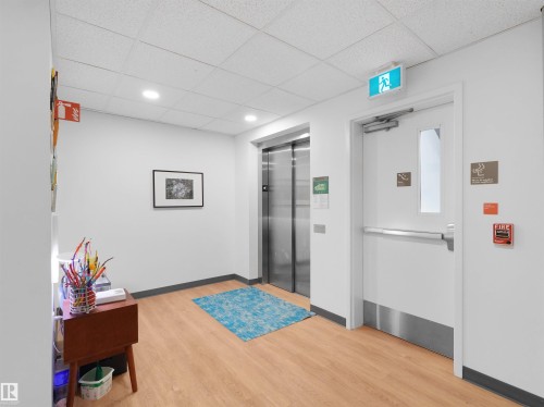 Modern commercial hallway featuring wood-finish flooring and a tiled ceiling with recessed lighting - 403 10115 88 Avenue, Edmonton, AB - Indoor Photo Showing Other Room