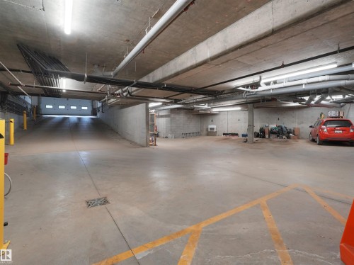 Underground parking garage featuring concrete flooring, exposed ceiling utilities, and fluorescent lighting - 403 10115 88 Avenue, Edmonton, AB - Indoor Photo Showing Garage