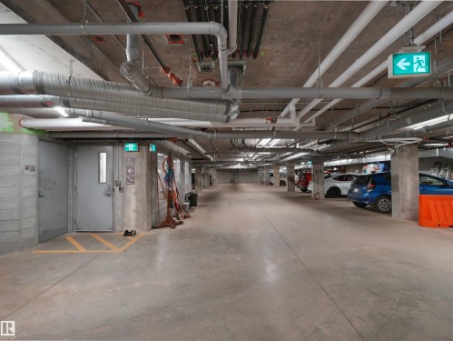 Underground parking garage featuring concrete flooring, exposed ceiling utilities, and multiple parking spaces - 403 10115 88 Avenue, Edmonton, AB - Indoor Photo Showing Garage
