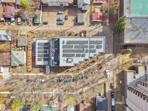 Multi-story building featuring multiple rooftop solar panel arrays, a flat roof design, and a light-colored exterior - 403 10115 88 Avenue, Edmonton, AB - 