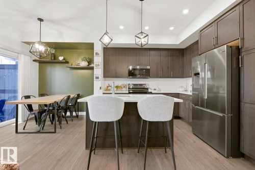 The kitchen features dark wood cabinetry, stainless steel appliances, and a central island with a white countertop - 405 Genesis Court, Stony Plain, AB - Indoor