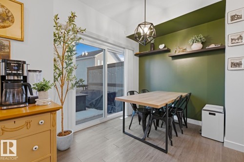 The dining area features a contrasting accent wall with shelving, an overhead light fixture, and a sliding glass door providing access to the outside - 405 Genesis Court, Stony Plain, AB - Indoor Photo Showing Dining Room
