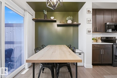 Dining area featuring an accent wall, a light-colored wood table, and direct access to an outdoor area via a sliding glass door - 405 Genesis Court, Stony Plain, AB - Indoor Photo Showing Kitchen