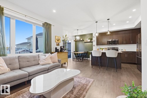 Open concept living space featuring a bright living room with large windows, a dining area, and a kitchen with dark cabinetry and an island - 405 Genesis Court, Stony Plain, AB - Indoor Photo Showing Living Room