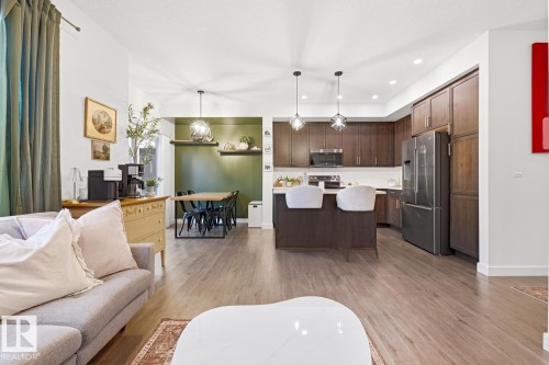 The property features an open-concept living area with hardwood flooring, a dining space with an accent wall and pendant lighting, and a kitchen equipped with stainless steel appliances, dark wood cabinetry, and a kitchen island with seating - 405 Genesis Court, Stony Plain, AB - Indoor Photo Showing Living Room