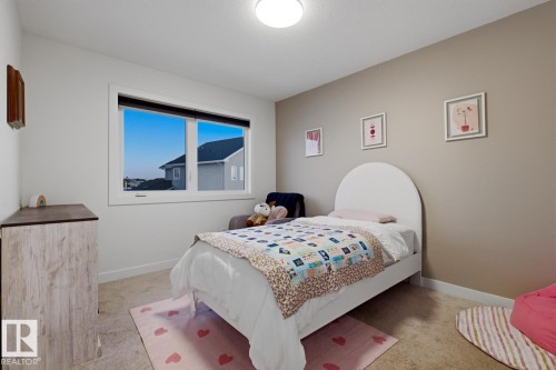 This room features light-colored walls, a large window, and carpeted flooring - 405 Genesis Court, Stony Plain, AB - Indoor Photo Showing Bedroom