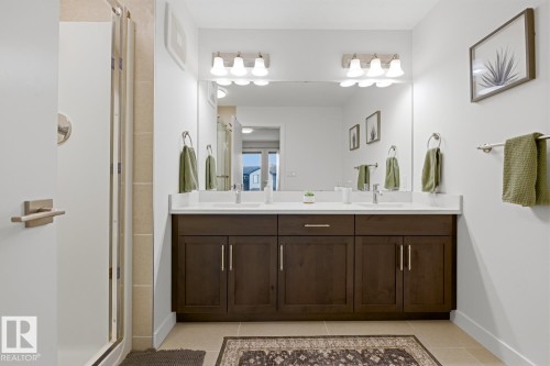 This bathroom features a large vanity with two sinks, a spacious mirror, and a modern light fixture - 405 Genesis Court, Stony Plain, AB - Indoor Photo Showing Bathroom