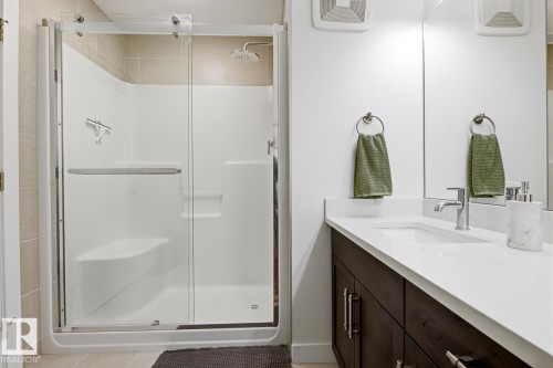 This bathroom features a contemporary vanity with a white countertop and dark wood cabinetry - 405 Genesis Court, Stony Plain, AB - Indoor Photo Showing Bathroom
