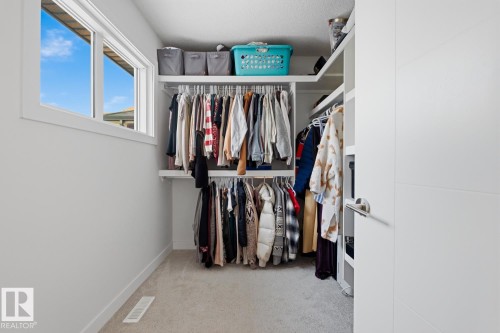 This room features built-in shelving and clothing racks, a window, and carpeted flooring - 405 Genesis Court, Stony Plain, AB - Indoor With Storage