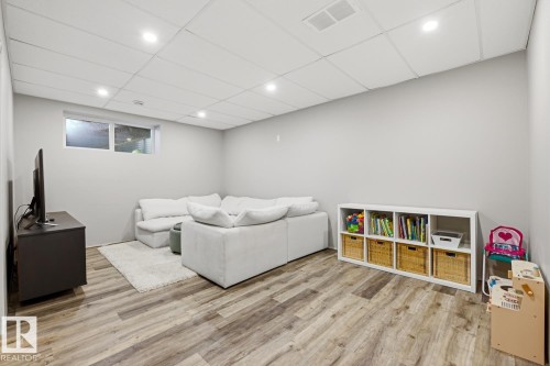 This finished living area features recessed lighting, durable wood-look flooring, and a window providing natural light - 405 Genesis Court, Stony Plain, AB - Indoor Photo Showing Basement