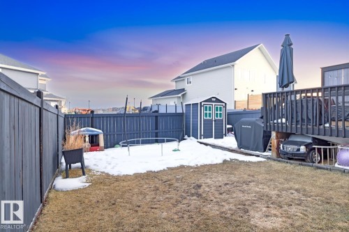 The property features a fenced yard, a storage shed with double doors, and a deck with dark railings - 405 Genesis Court, Stony Plain, AB - Outdoor With Exterior