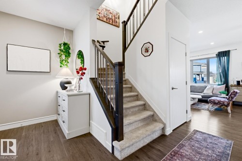 The property features hardwood flooring and a carpeted staircase with dark wood railings - 405 Genesis Court, Stony Plain, AB - Indoor Photo Showing Other Room
