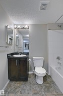 Bathroom featuring a dark wood-finish vanity with a dark countertop, white oval sink, and chrome fixtures - 