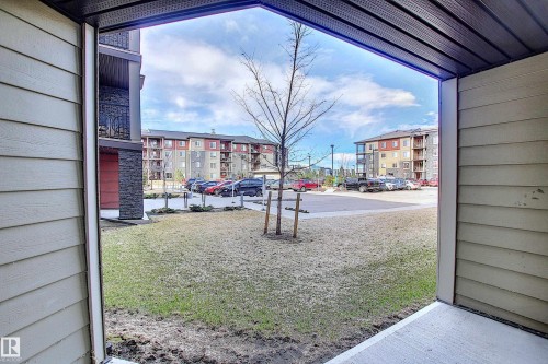 Patio entrance featuring light beige siding, a concrete pad, and a textured black soffit - 114 3207 James Mowatt Trail, Edmonton, AB - Outdoor With Exterior