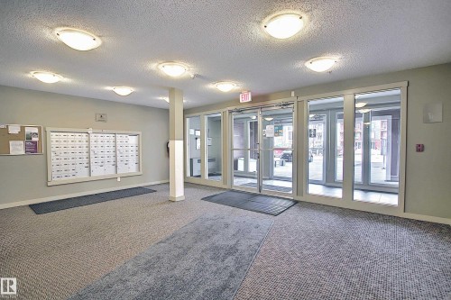 Entry foyer featuring patterned carpeting, multiple flush-mount ceiling lights, and a wall-mounted mailbox system - 114 3207 James Mowatt Trail, Edmonton, AB - Indoor Photo Showing Other Room