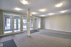 Spacious common area featuring textured carpet flooring, neutral painted walls, and multiple flush-mount ceiling lights - 