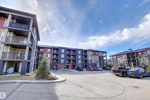 Multi-level residential building featuring a stone and siding exterior with private balconies and patios - 114 3207 James Mowatt Trail, Edmonton, AB - Outdoor With Facade