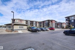 Multi-story residential buildings featuring varied siding, balconies, and an onsite parking area with a separate single-story structure - 