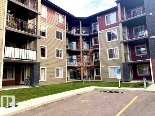 Multi-story residential building featuring two-tone horizontal siding, multiple balconies with black metal railings, and stone veneer accents - 114 3207 James Mowatt Trail, Edmonton, AB - Outdoor With Facade