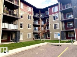 Multi-story residential building featuring two-tone horizontal siding, multiple balconies with black metal railings, and stone veneer accents - 