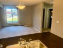 Spacious living area featuring a sliding glass door, neutral-toned carpet, and a contemporary chandelier - 114 3207 James Mowatt Trail, Edmonton, AB  - Indoor Photo Showing Other Room 