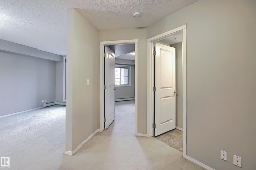 Interior hallway with light gray painted walls and white baseboards - 114 3207 James Mowatt Trail, Edmonton, AB - Indoor Photo Showing Other Room