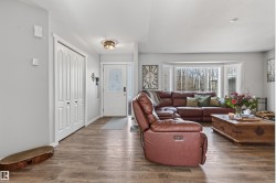 Living space with wood-finish flooring, white walls, and a prominent bay window - 