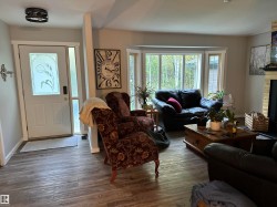 Bright living space featuring wood-finish flooring and a white front entry door with decorative glass - 