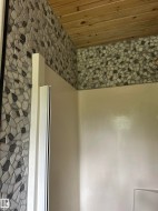 Shower enclosure featuring a wood-panel ceiling and mosaic stone tile - 