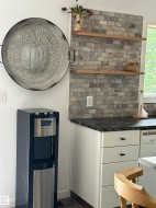 Kitchen corner featuring a textured stone-look backsplash and two open wood shelves - 