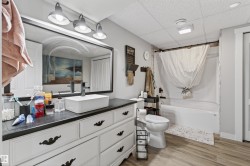 Bathroom vanity with a rectangular vessel sink, black faucet, and a large framed mirror with a four-light fixture - 
