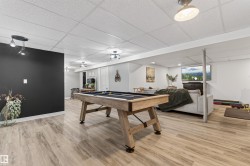 Finished lower level featuring wood-finish flooring, a drop ceiling with recessed lighting, and a dedicated entertainment area - 