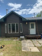 Exterior featuring horizontal siding, a multi-pane bay window, and a white entry door with frosted glass detailing - 