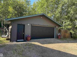 Detached garage with horizontal siding and a dark panel garage door - 
