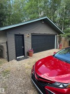 Detached garage with horizontal siding, a paneled garage door, and a side entry door - 