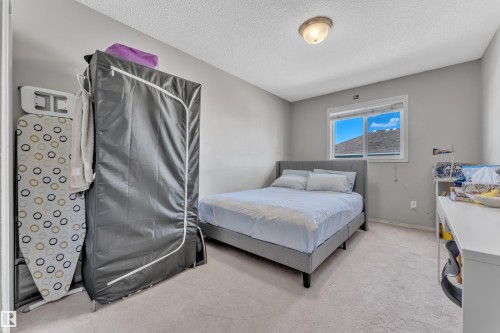 Bright room featuring neutral wall paint, light-colored carpet flooring, a window with white trim, and a ceiling-mounted light fixture - 64 4350 23 Street, Edmonton, AB - Indoor Photo Showing Bedroom