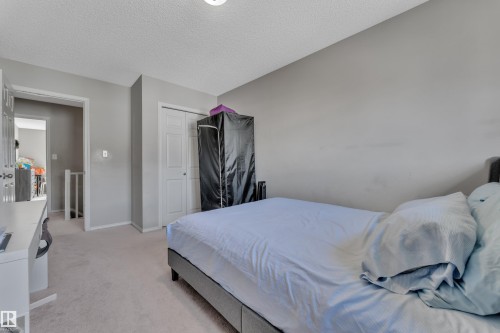 Neutral-toned room featuring light gray walls, textured white ceilings, and light-colored carpet flooring - 64 4350 23 Street, Edmonton, AB - Indoor Photo Showing Bedroom