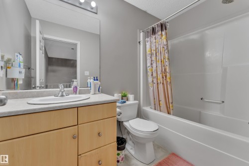 Bathroom featuring a single vanity with light wood-finish cabinetry, a white basin sink, and a light gray countertop - 64 4350 23 Street, Edmonton, AB - Indoor Photo Showing Bathroom