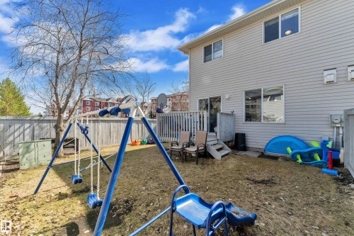 Rear exterior featuring horizontal siding, multiple windows, and a sliding glass door leading to a wooden deck - 64 4350 23 Street, Edmonton, AB - Outdoor