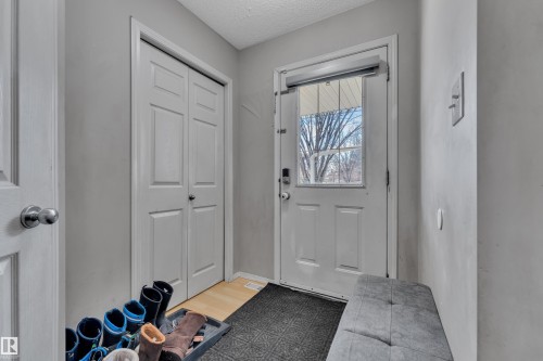 Front entry featuring a paneled door with glass insert, a built-in closet with bi-fold doors, and light gray wall paint - 64 4350 23 Street, Edmonton, AB - Indoor Photo Showing Other Room