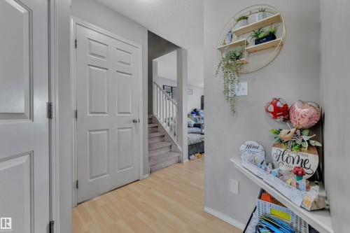 Hallway featuring light wood-finish flooring, white paneled doors, and a carpeted staircase with white railings - 64 4350 23 Street, Edmonton, AB - Indoor Photo Showing Other Room